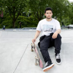 Portrait d'un adolescent posant assis sur une structure de ciment gris avec un skateboard (planche à roulettes) à la main, issu du reportage photographie de Richard Baron (membre de Light Motiv) sur la mobilité urbaine des jeunes à Lille pour le magazine Phosphore, numéro 34, septembre 2024