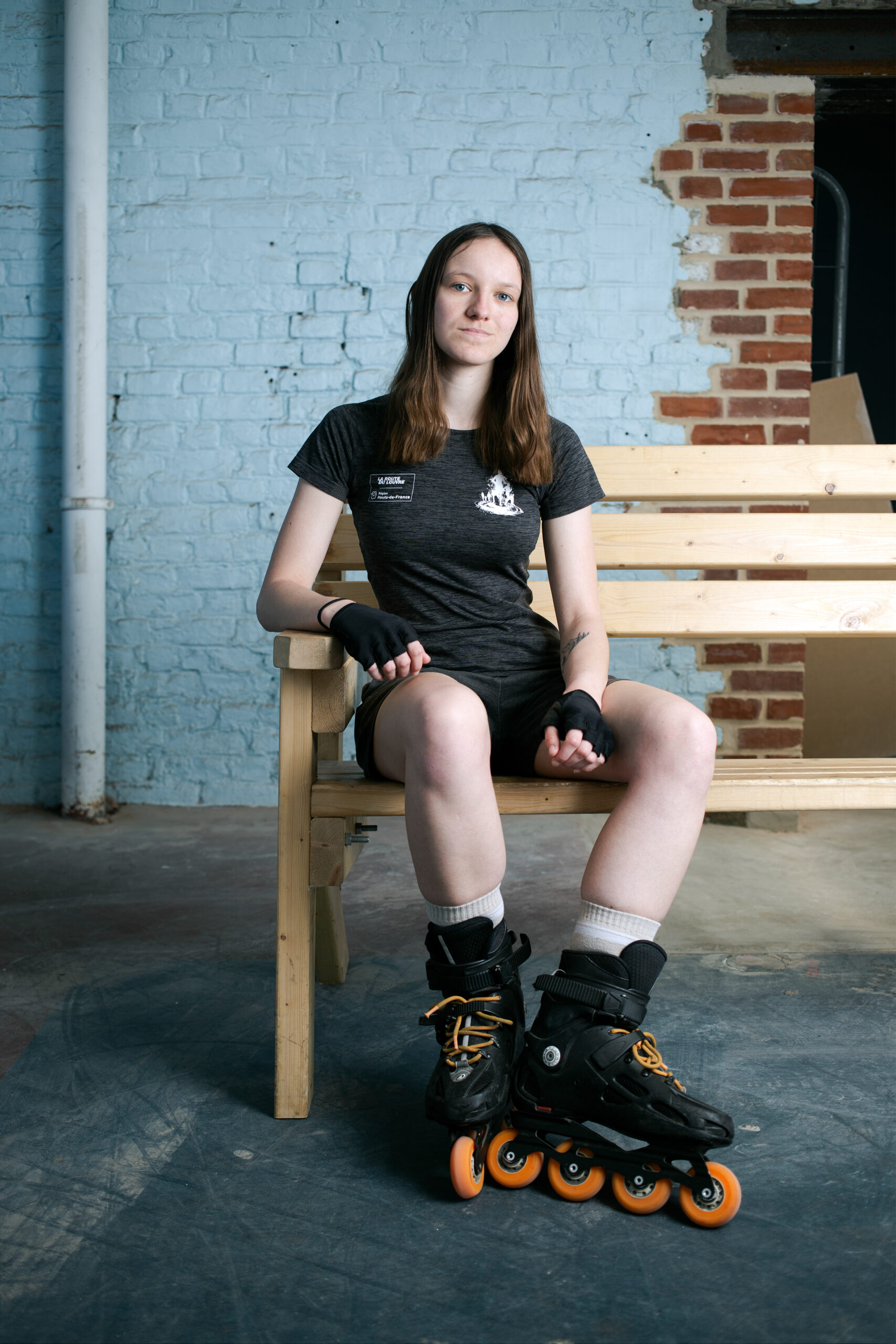 Portrait d'une adolescente assise sur un banc de bois et chaussée d'une paire de rollers, issu du reportage photographie de Richard Baron (membre de Light Motiv) sur la mobilité urbaine des jeunes à Lille pour le magazine Phosphore, numéro 34, septembre 2024